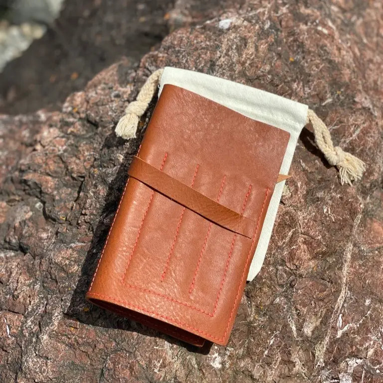 Brown leather wallet with drawstring on a textured stone surface